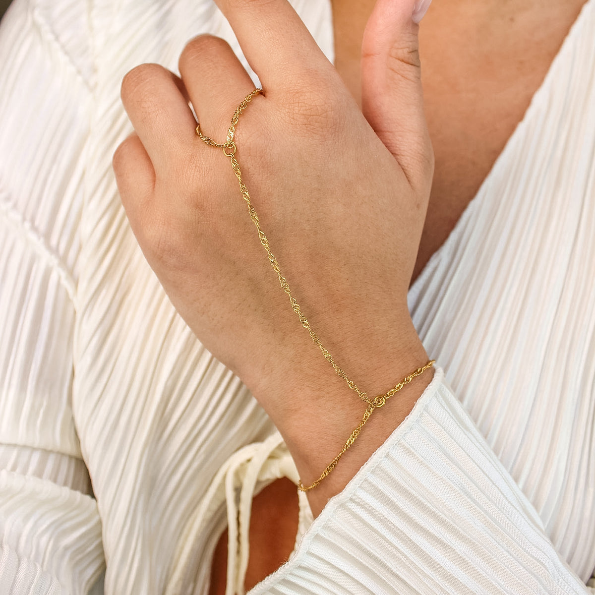 Gold bracelet on a person's wrist with a white background