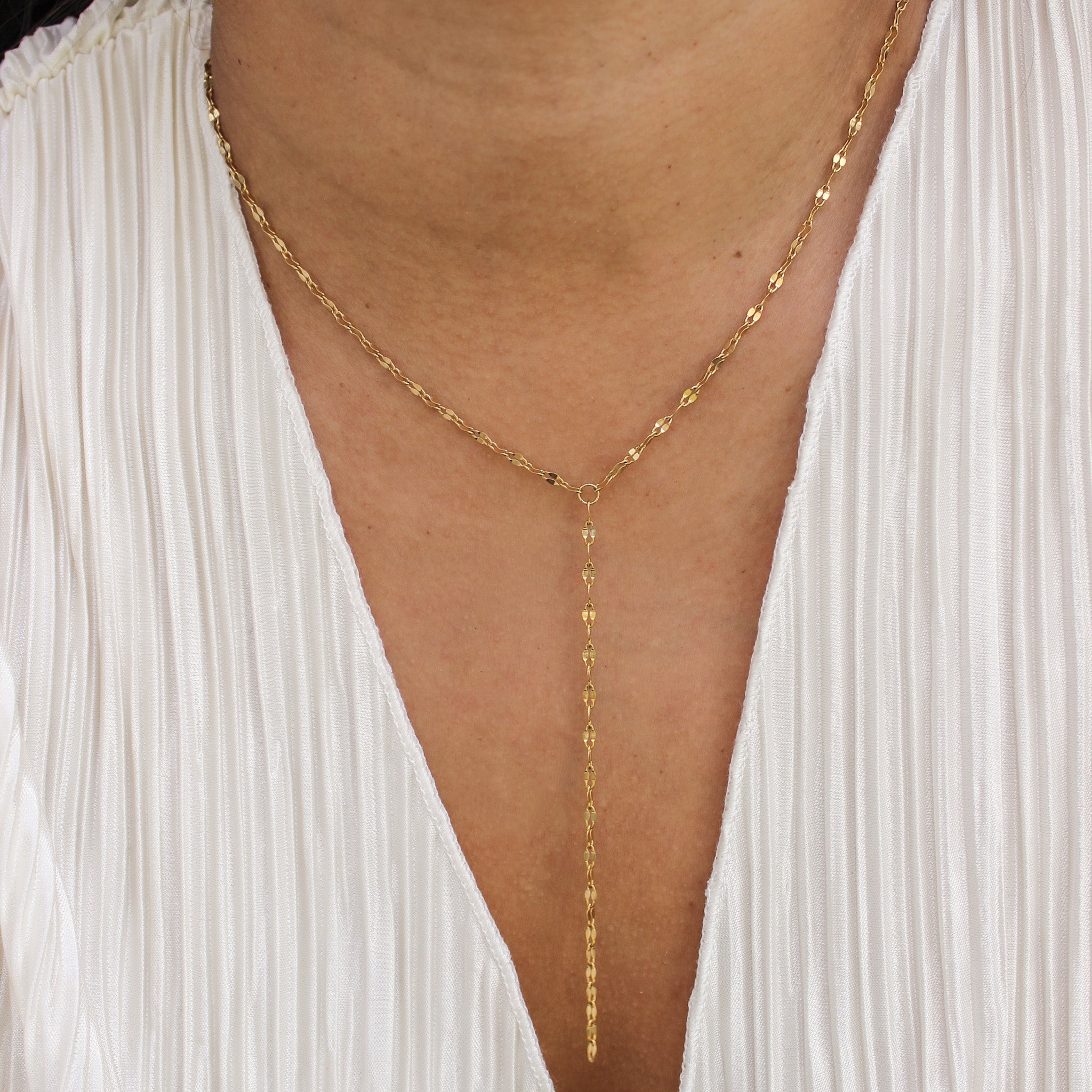 Gold chain necklace worn by a person with a white garment