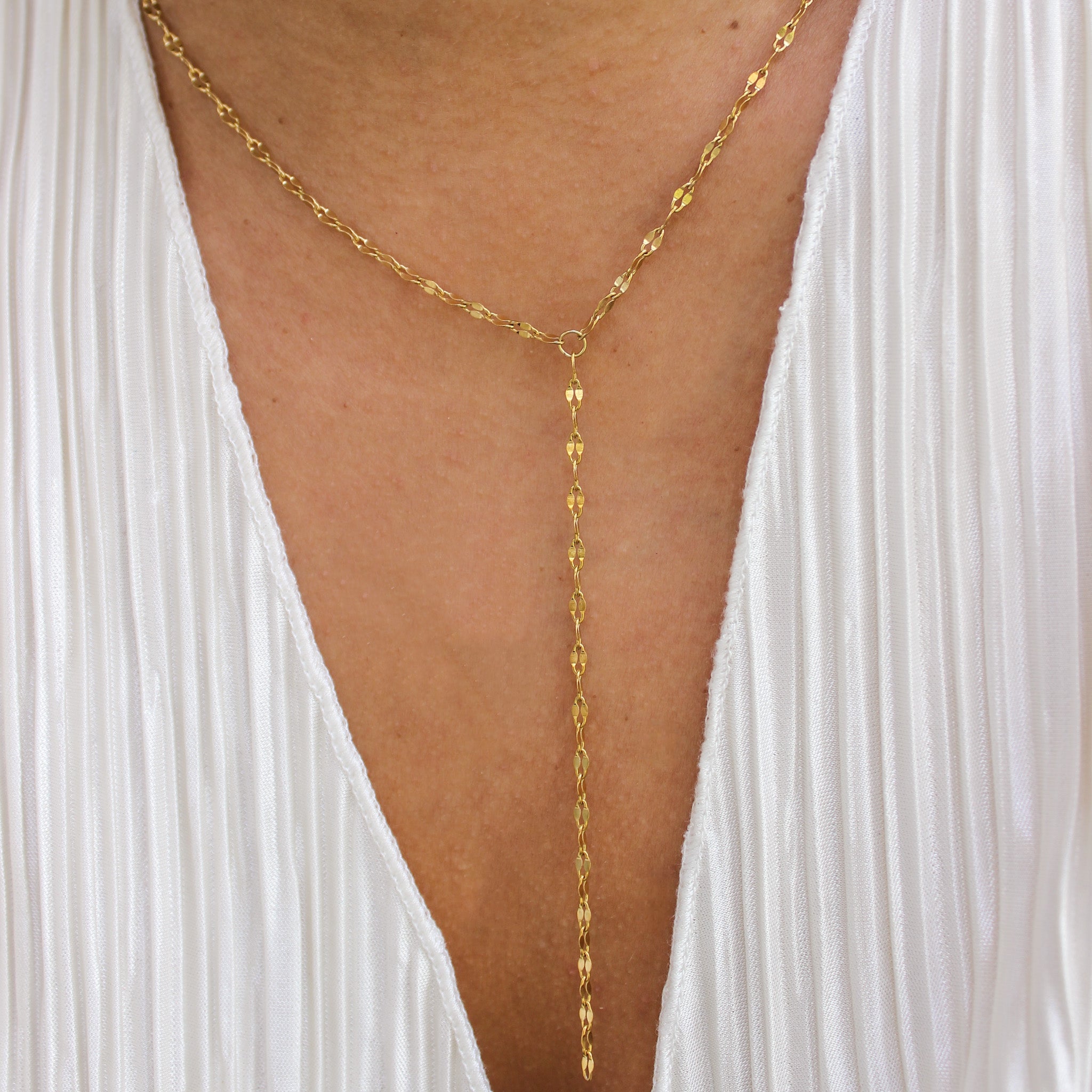 Gold body chain worn with a white dress