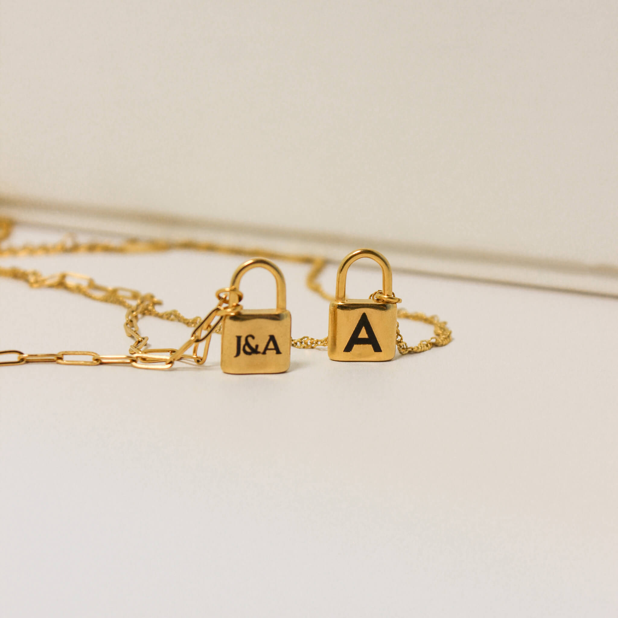 Gold necklace with lock pendants on a light background