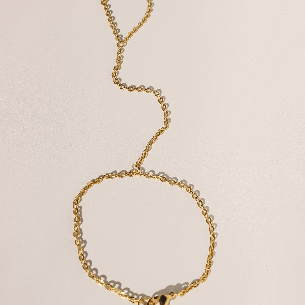 Gold chain bracelet on a beige background