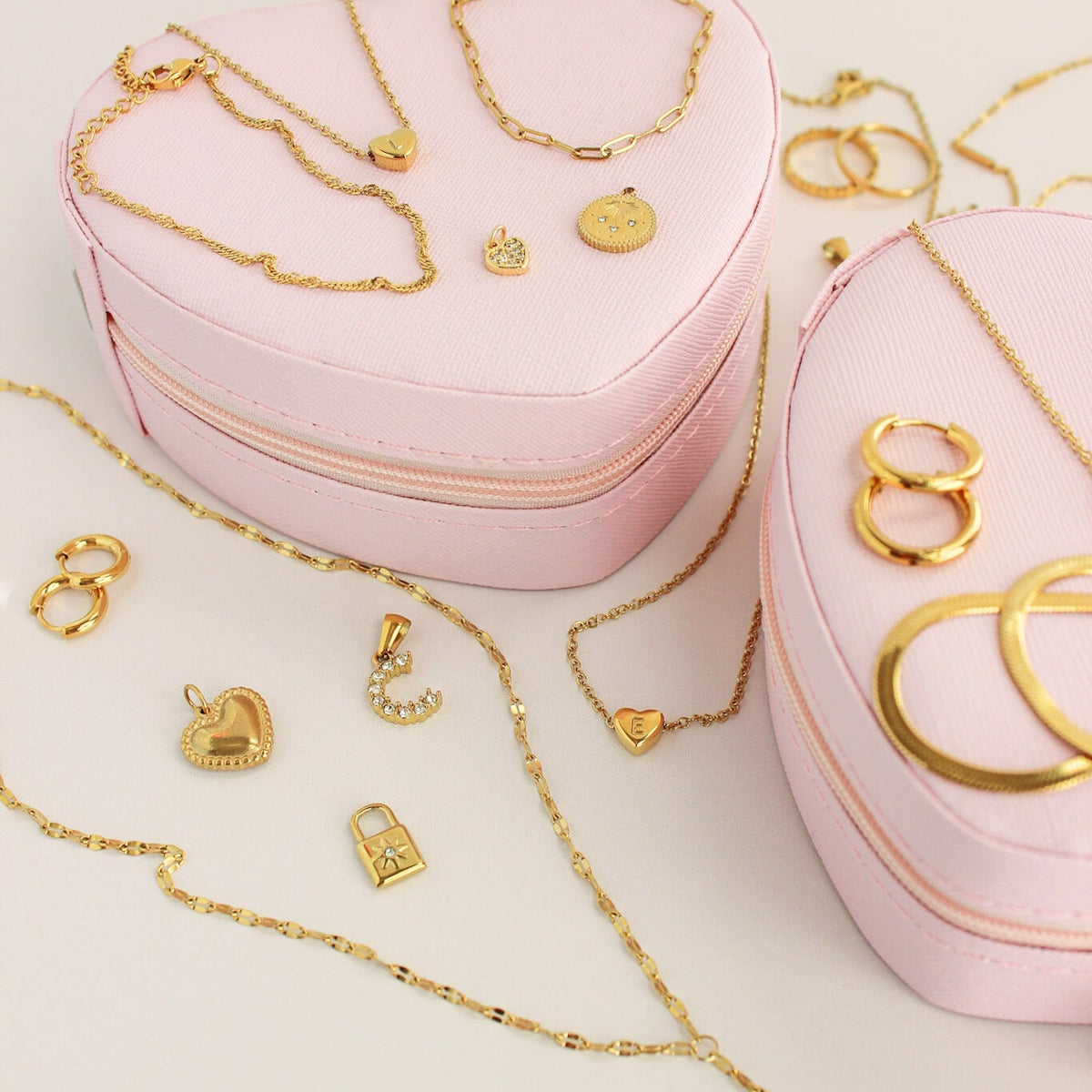 Heart-shaped pink jewelry box with gold jewelry on a light background