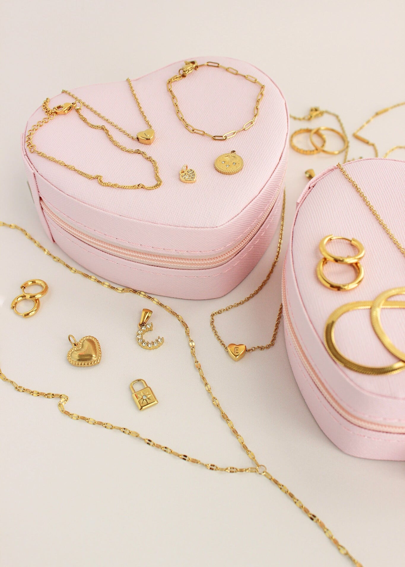 Heart-shaped pink jewelry box with gold jewelry on a light background