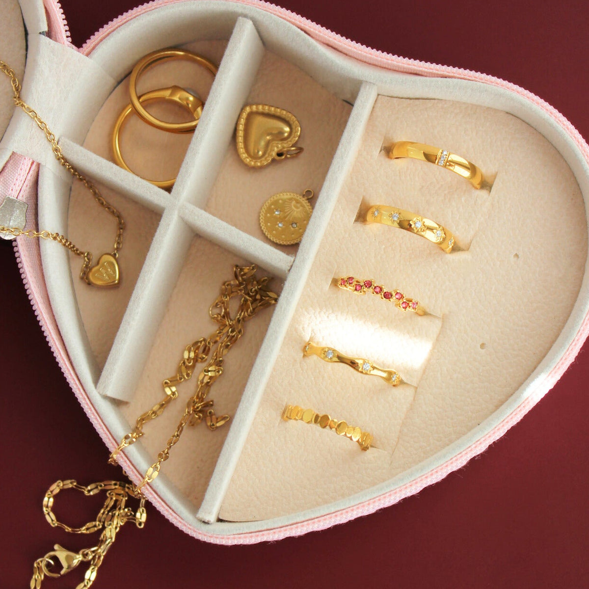Heart-shaped jewelry box with gold jewelry on a red background