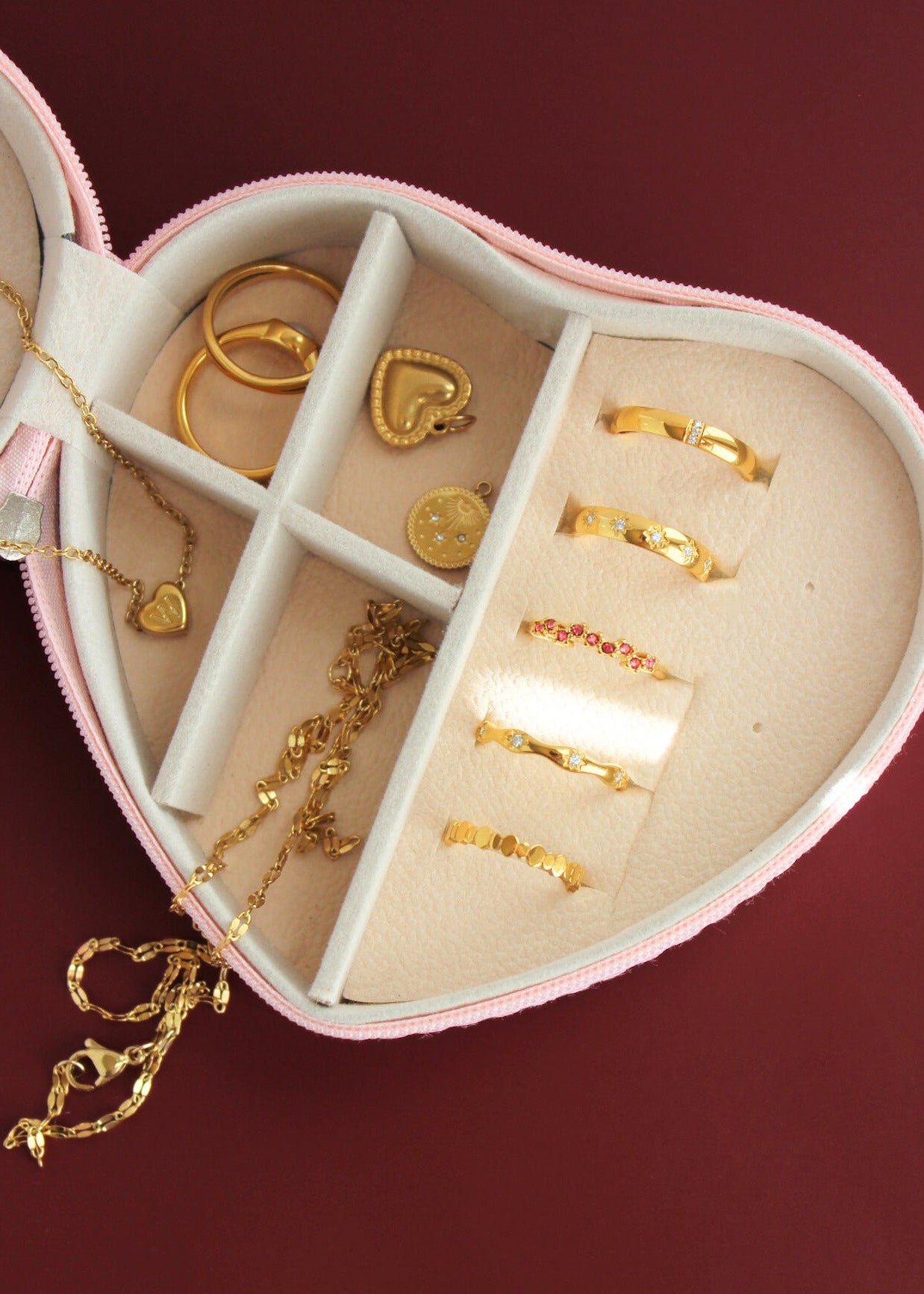 Heart-shaped jewelry box with gold jewelry on a red background