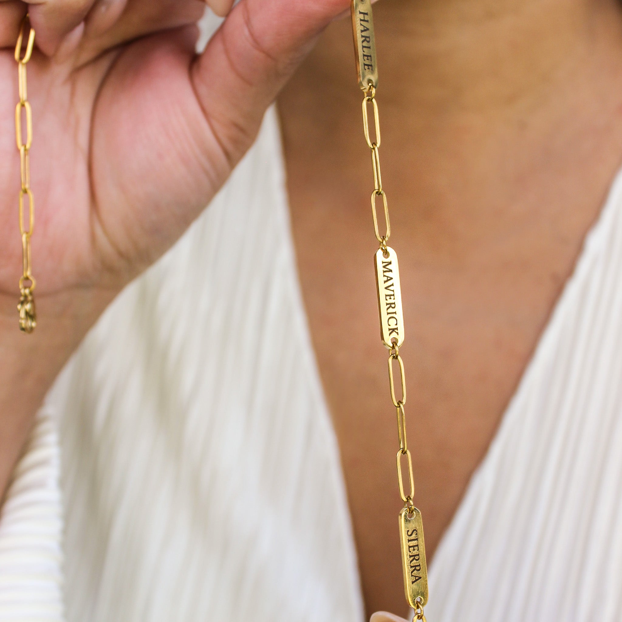 Gold chain necklace with engraved names on a white background