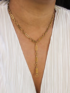 Gold chain necklace worn by a person against a white background
