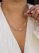 Gold chain necklace being adjusted on a person wearing a white top.