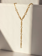 Gold chain necklace on a white surface with soft shadows
