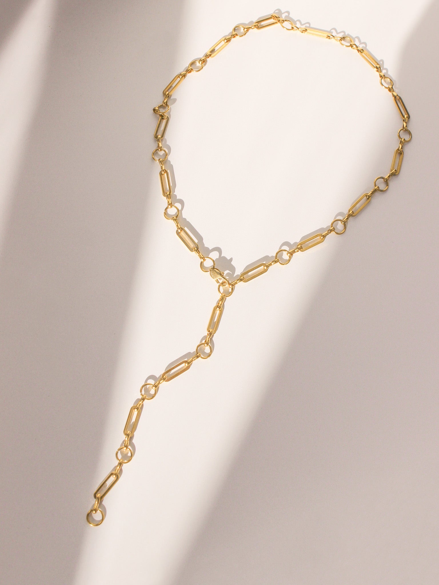 Gold chain necklace with pearl-like beads on a beige background