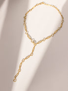 Gold chain necklace with pearl-like beads on a beige background