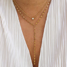 Gold body chain worn over a white sheer garment