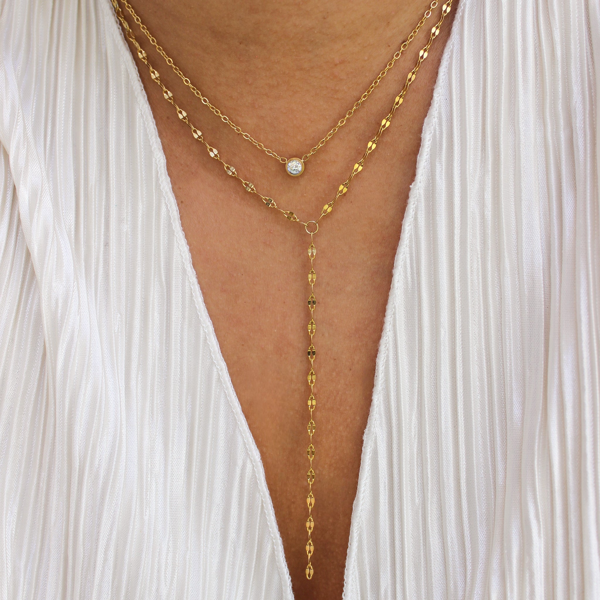 Gold body chain worn over a white sheer garment