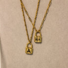 Two gold padlock necklaces on a beige background