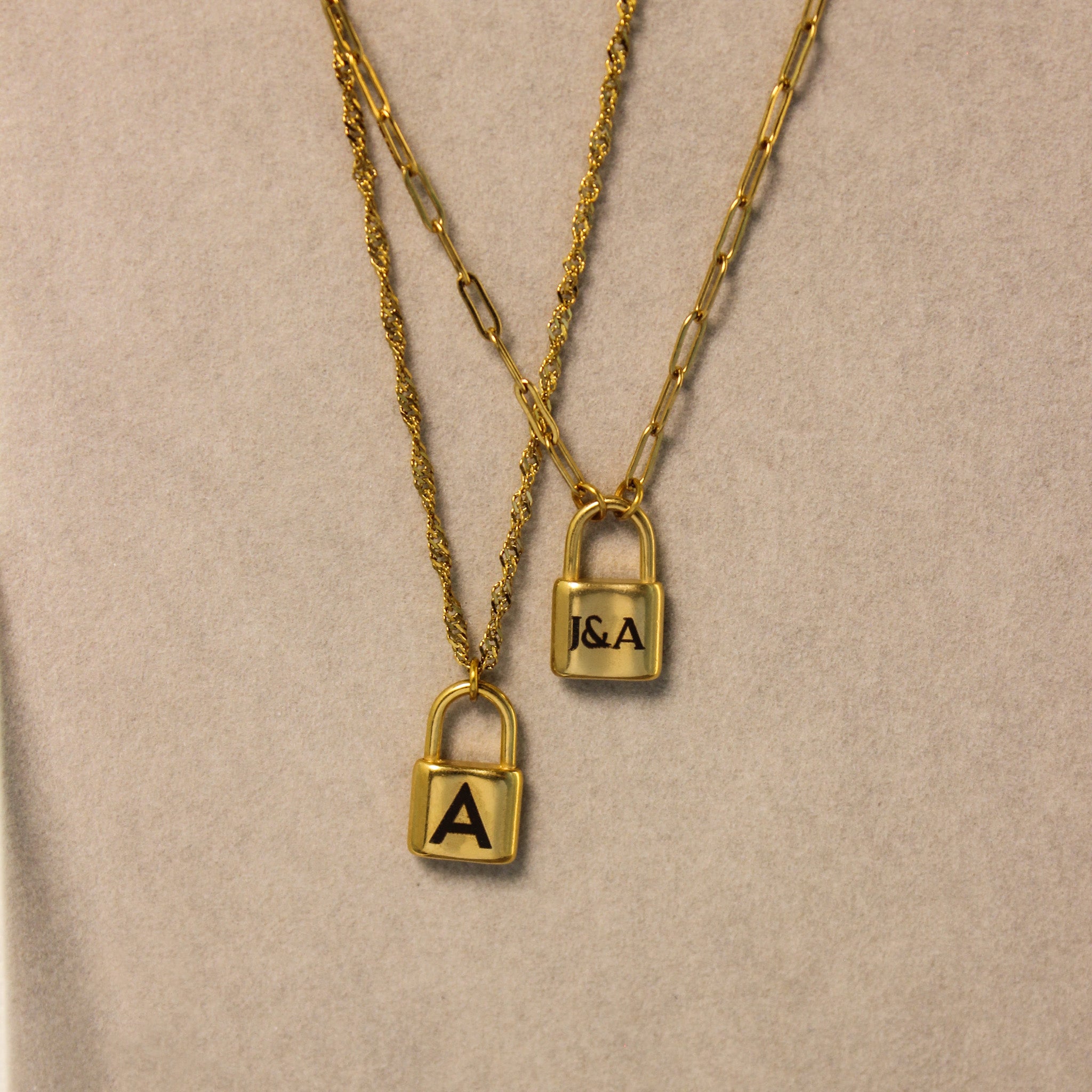 Two gold padlock necklaces on a beige background