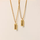 Two gold necklaces with engraved text on a beige background