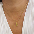 Gold necklace with a '1995' pendant worn by a person against a white background