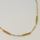 Gold chain bracelet with engraved names on a light gray background