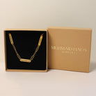Gold necklace in a 'Mermaid Haus Jewelry' box on a beige background